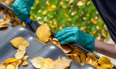 removing debris from a Crossroads gutter by hand